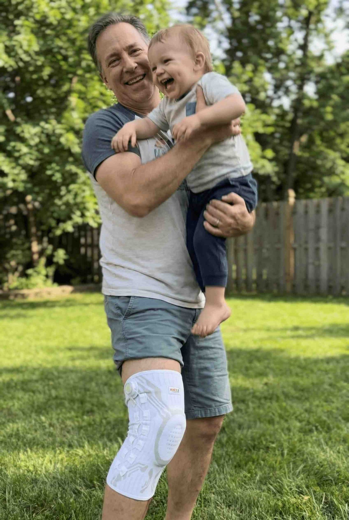 Holding a child outdoors wearing the knee brace