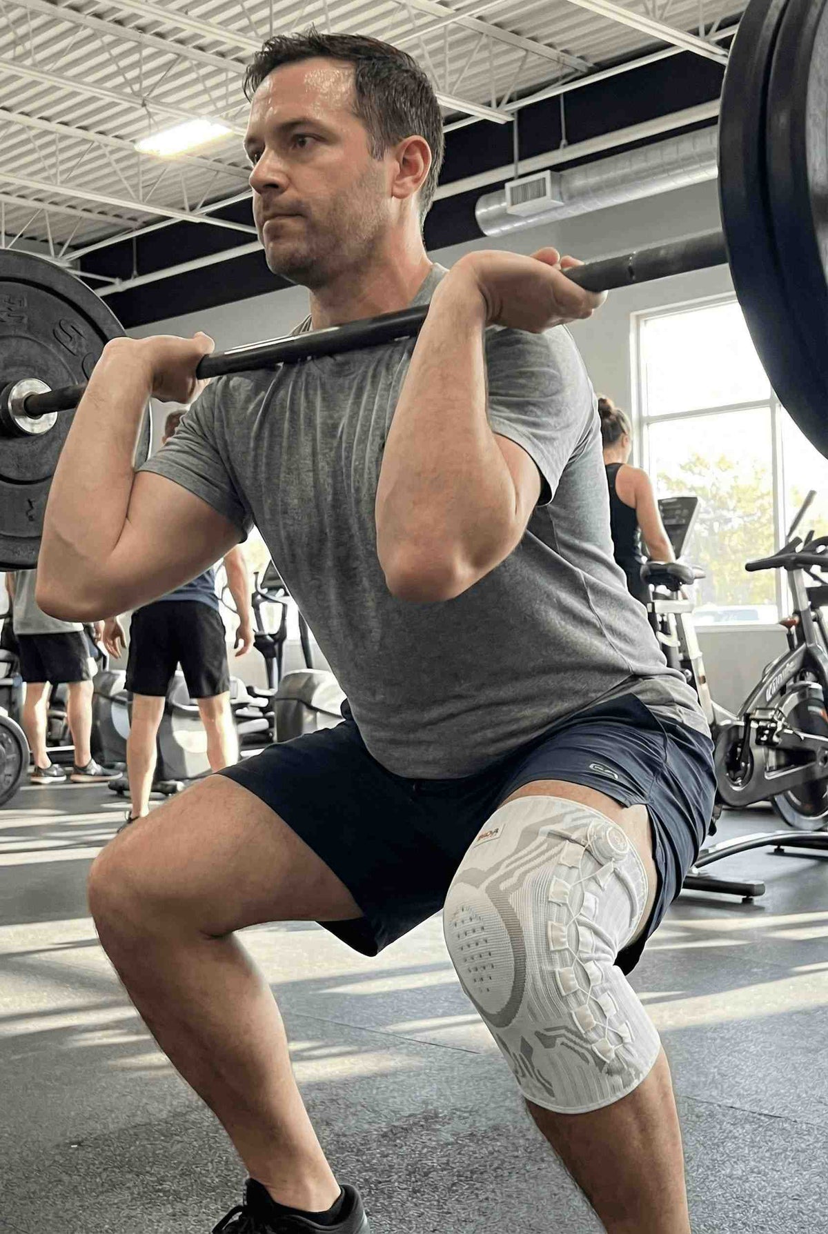 Squatting in the gym wearing the knee brace